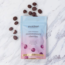 Load image into Gallery viewer, Dark Chocolate Montmorency Cherries pouch on marble with loose chocolate-covered cherries scattered around it