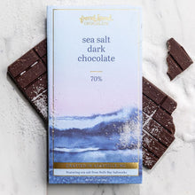 Load image into Gallery viewer, Sea Salt Dark Chocolate 70% bar package atop unwrapped salt-sprinkled dark chocolate with scattered sea salt on marble.
