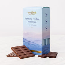 Load image into Gallery viewer, Carolina Crafted Chocolate 6 Bar Collection box with mountain artwork beside unwrapped chocolate bars on white marble.
