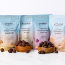 Load image into Gallery viewer, Treat Yourself Gift Set: four French Broad Chocolates treat pouches lined up with wooden bowls of chocolate-covered pieces
