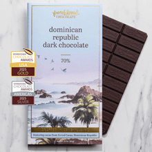 Load image into Gallery viewer, Dominican Republic Dark Chocolate 70% bar beside its tropical watercolor wrapper on a marble surface.
