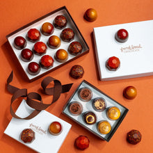 Load image into Gallery viewer, Caramel Lovers Gift Set with open boxes of fall caramels and Asheville Crafted bonbons, ribbon and lids on an orange surface.
